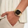 Goudkleurig en zwart analoog horloge